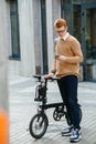 Busy handsome young man with ebike and phone on the street.