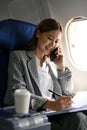 A busy and hardworking Asian businesswoman on the phone while flying to another city