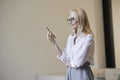Busy hours. Stylish mature blonde woman in glasses and business attire smiling and talking on the phone, standing Royalty Free Stock Photo