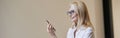 Busy hours. Stylish mature blonde woman in glasses and business attire smiling and talking on the phone, standing Royalty Free Stock Photo