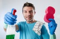 Busy husband smiling happy doing house cleaning with spray bottle and sponge washing glass