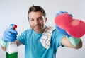 Busy husband smiling happy doing house cleaning with spray bottle and sponge washing glass