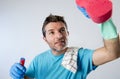 Busy husband smiling happy doing house cleaning with spray bottle and sponge washing glass