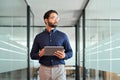 Busy Indian business man looking away holding tab walking in office.