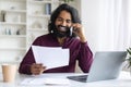 Busy Indian Freelancer Guy Checking Papers And Talking On Cellphone At Home Royalty Free Stock Photo