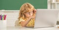 busy kid boy in glasses study online in school classrrom with computer, school Royalty Free Stock Photo