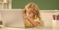 busy kid boy in glasses study online in school classrrom with computer, school Royalty Free Stock Photo