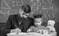 Busy kid studying at school. Teacher, father checking homework, helps to boy, son. Teacher in formal wear and pupil in Royalty Free Stock Photo