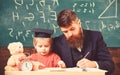 Busy kid studying at school. Teacher, father checking homework, helps to boy, son. Teacher in formal wear and pupil in Royalty Free Stock Photo