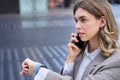 Busy lady manager talking on mobile phone on street, going on a meeting, checking time on watch Royalty Free Stock Photo