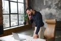 Busy male office employee standing near office desk, talking on the smartphone Royalty Free Stock Photo