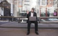 busy man sits on a public transit stop and works on a laptop. Work on the way to the office