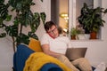 Busy man sitting on couch with laptop. Serious guy with glasses talking on phone, focused on work Royalty Free Stock Photo