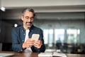 Busy mature business man entrepreneur sitting at desk using mobile cell phone.