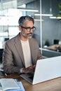 Busy mature business man ceo looking at laptop working in office. Vertical.