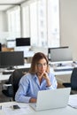 Busy mature business woman using laptop working in office. Vertical Royalty Free Stock Photo