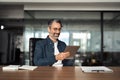 Busy mature older business man executive sitting in office using tablet.