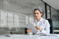 Busy mature professional business woman using tablet computer in office. Royalty Free Stock Photo