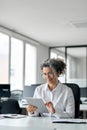 Busy mature professional business woman using tablet in office, vertical. Royalty Free Stock Photo