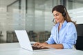 Busy mature woman call center support agent in headset using laptop in office. Royalty Free Stock Photo