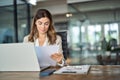 Busy mid aged business woman working in office with laptop and documents. Royalty Free Stock Photo