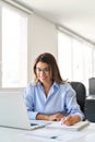 Busy middle aged business woman working on laptop writing notes in office. Royalty Free Stock Photo