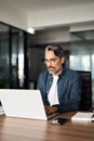 Busy middle aged Indian business man using laptop computer in office. Vertical. Royalty Free Stock Photo