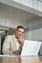 Busy middle aged professional businessman using laptop working at desk. Vertical Royalty Free Stock Photo