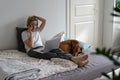 Busy middle-aged woman talks on smartphone with important person sitting on bed near dog Royalty Free Stock Photo