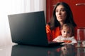 Worried Woman Working a Laptop Holding Her Baby Royalty Free Stock Photo