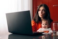 Worried Woman Working a Laptop Holding Her Baby Royalty Free Stock Photo