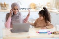 Busy Muslim Mom Trying To Work While Her Little Daughter Asking Attention Royalty Free Stock Photo