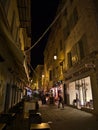 Busy night scene in downtown of Nice, France at the French Riviera with people walking through illuminated narrow alley.