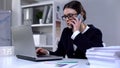 Busy office manager answering phone call while typing on laptop, stressful day Royalty Free Stock Photo