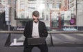 Busy office worker sits at a bus stop and works on a laptop. Work on the bench while on the road to work