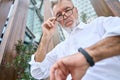 Busy older senior business man looking at wristwatch standing outdoors.