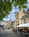 Busy outdoor cafes in front of the Penniless Porch and Bishops Palace gateway in Market Place, Wells, Somerset, UK