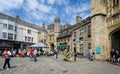 Busy outdoor cafes in front of the Penniless Porch on Market saturday in Market Place, Wells, Somerset, UK