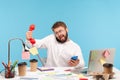 Busy overworked man sitting at workplace all covered with sticky notes and holding three phones in hands, answering calls, service