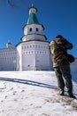 A busy photographer is taking a picture in front of the tower and fortress wall of the New Jerusalem Monastery. Istra, Russia. Royalty Free Stock Photo