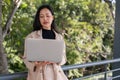 A busy, professional Asian businesswoman is working on her laptop outdoors on the skywalk Royalty Free Stock Photo