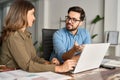 Busy professional workers working in office with laptop and talking. Royalty Free Stock Photo