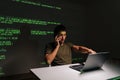Busy programmer male sitting at desk with laptop, deeply engaged in phone conversation while analyzing projected green Royalty Free Stock Photo