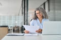 Busy smiling mature old business woman working in office checking documents. Royalty Free Stock Photo