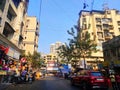 Busy street road in Bandra India Mumbai with shops in corner and vegetable vendor sitting