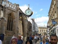 Busy Street Scene with Large Clock With Ornate Bracket on Medieval Building