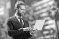 busy successful businessman in suit working on laptop standing outdoor, modern life