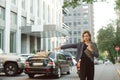 Busy successful businesswoman in formal wear catching a taxi on street of modern city near the office. Concentrated caucasian