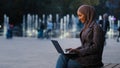 Busy successful muslim student girl in hijab islamic business woman freelancer using laptop app working in city