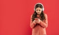 busy teen girl in sweater in headphones for listening music texting in phone, copy space, technology